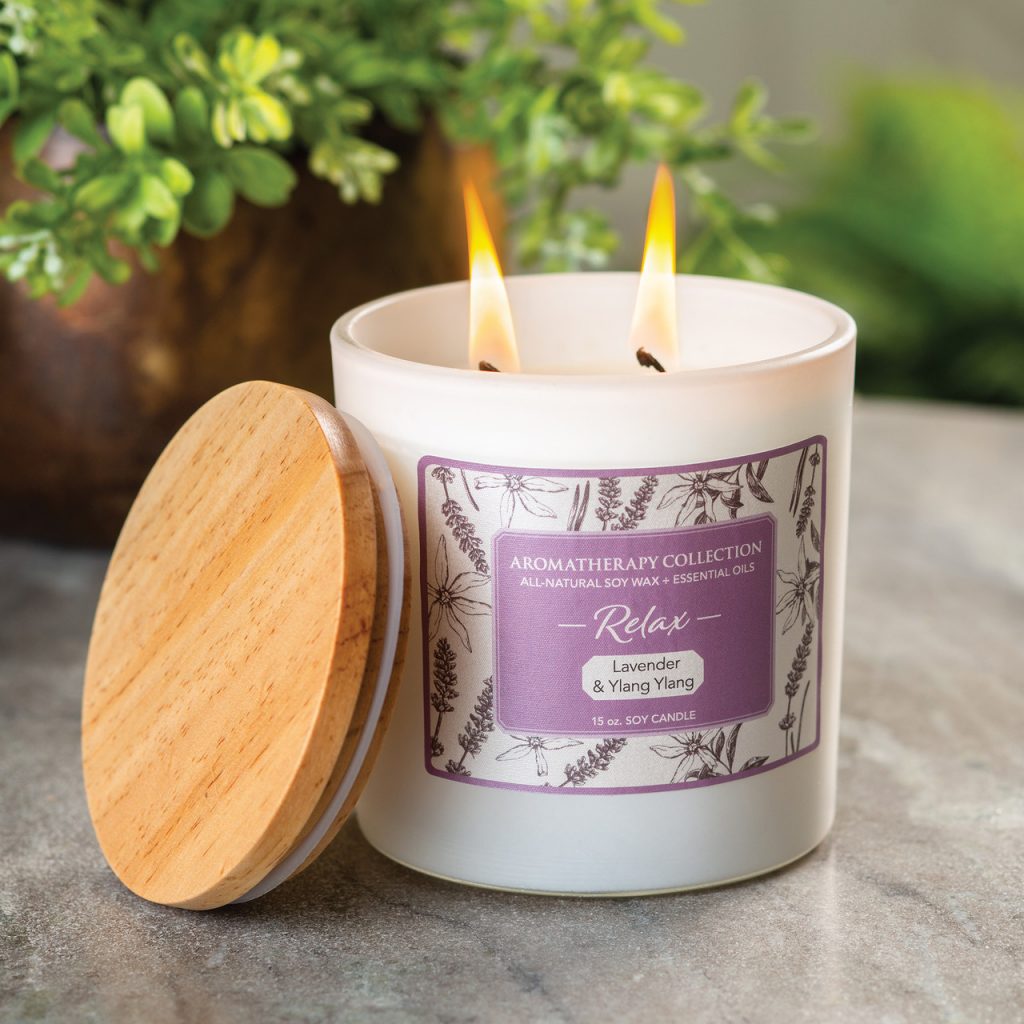 Lit two-wick soy candle in white glass jar with wooden lid, purple Aromatherapy Collection Relax label, Lavender & Ylang Ylang, 15 oz.