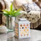 Add a touch of elegance to your home with the Trellis Lantern Canopy Illumination Warmer. Inspired by on-trend trellis patterns, this elegant warmer features a metal handle and is accented with a halogen bulb that warms wax melts in the warming dish to fill large areas with fragrance.