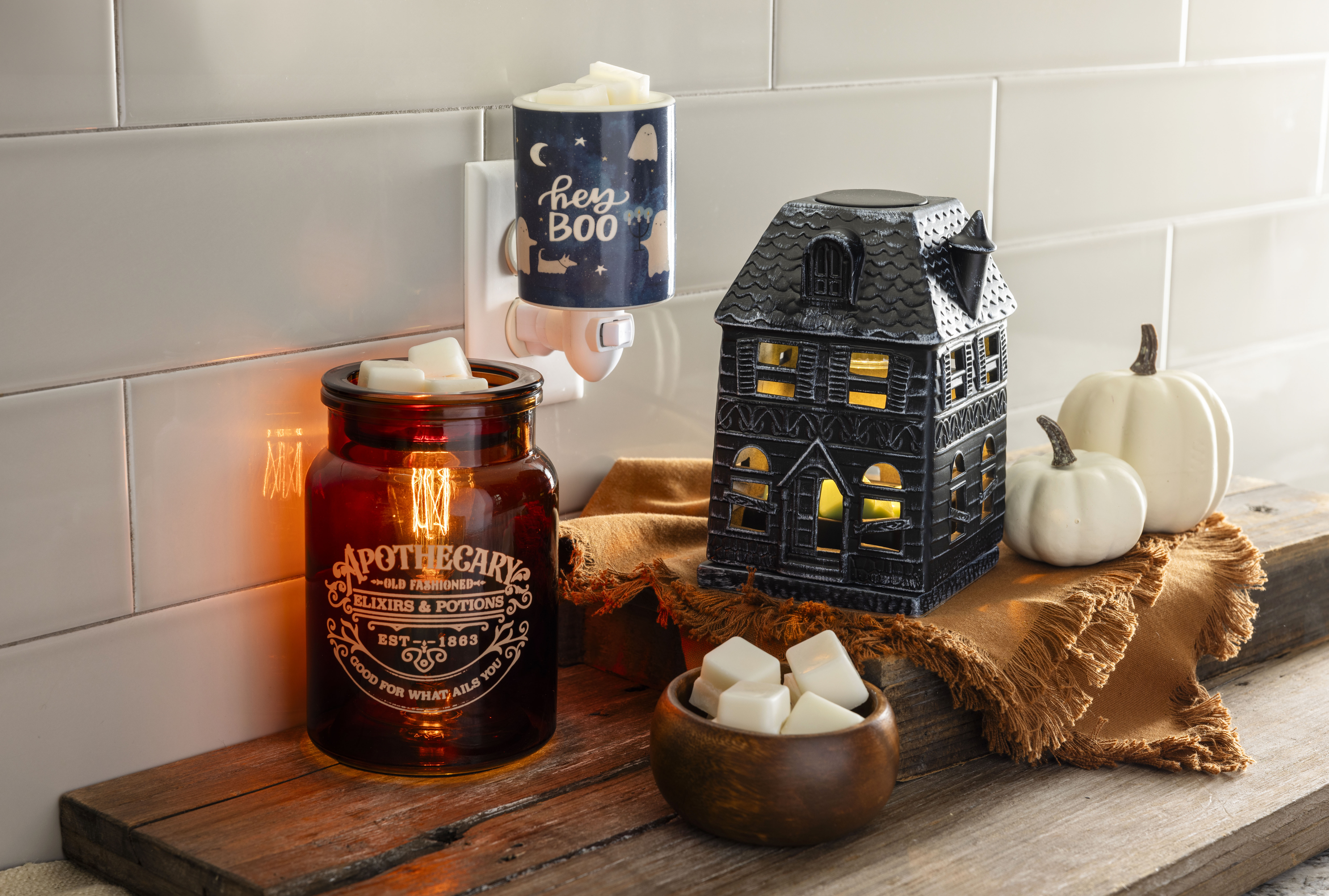 Halloween display with an apothecary jar candle, 'hey Boo' ghost plug-in and haunted house warmer