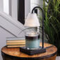 Elevate your space with the sophisticated Lumiere Candle Warmer Lamp. The sleek black design and clear glass shade provide a modern touch, while the glass flutes cast a stunning decorative glow. Using advanced top-down warming technology, this lamp allows you to enjoy the aroma and ambiance of your favorite candles without the need for an open flame. It also features an adjustable stem and a convenient timer/dimmer switch for personalized comfort.