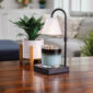 Elevate your space with the sophisticated Lumiere Candle Warmer Lamp. The sleek black design and clear glass shade provide a modern touch, while the glass flutes cast a stunning decorative glow. Using advanced top-down warming technology, this lamp allows you to enjoy the aroma and ambiance of your favorite candles without the need for an open flame. It also features an adjustable stem and a convenient timer/dimmer switch for personalized comfort.