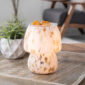 The Art Glass Lamp Vintage Illumination Warmer blends midcentury charm with timeless elegance. Its all-glass design features a white and clear pattern that glows softly orange when lit. With a vintage bulb and glass wax tray, it offers a flame-free way to enjoy fragrance while adding a stylish touch to any room.