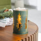 Bring the serene beauty of nature indoors with our Golden Pines Illumination Wax Warmer. Glowing pine tree cutouts cast soft patterns, while a vintage bulb adds a warm golden light. The green distressed metal finish offers rustic charm, blending nature-inspired design with cozy, vintage appeal.