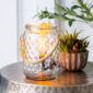 The Art Glass Lamp Vintage Illumination Warmer blends midcentury charm with timeless elegance. Its all-glass design features a white and clear pattern that glows softly orange when lit. With a vintage bulb and glass wax tray, it offers a flame-free way to enjoy fragrance while adding a stylish touch to any room.