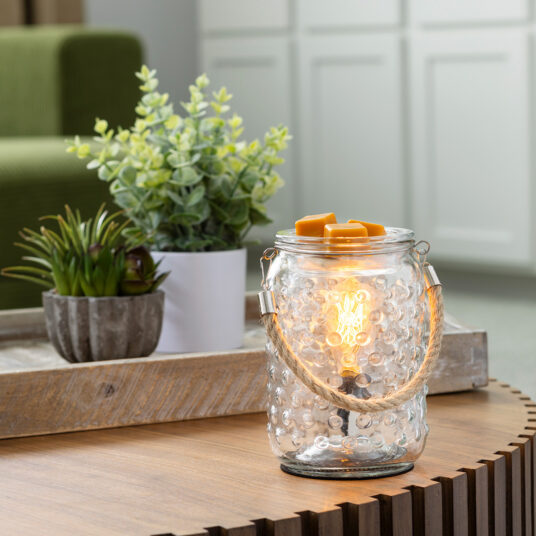 The Art Glass Lamp Vintage Illumination Warmer blends midcentury charm with timeless elegance. Its all-glass design features a white and clear pattern that glows softly orange when lit. With a vintage bulb and glass wax tray, it offers a flame-free way to enjoy fragrance while adding a stylish touch to any room.