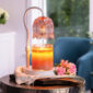 The Tulip Candle Warmer Lamp pairs a soft pink floral-shaped shade with a sleek white base for vintage-inspired elegance.