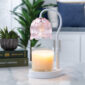 The Tulip Candle Warmer Lamp pairs a soft pink floral-shaped shade with a sleek white base for vintage-inspired elegance.