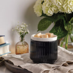Glossy black ribbed ceramic meets a crisp white removable dish in the Noir Wax Warmer for a striking, modern silhouette that elevates contemporary decor.