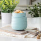 The Ruche Wax Warmer features a softly ribbed texture and light teal glaze to add subtle, modern charm to your home.