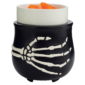 Black skeleton-hand design wax warmer holding orange melted wax